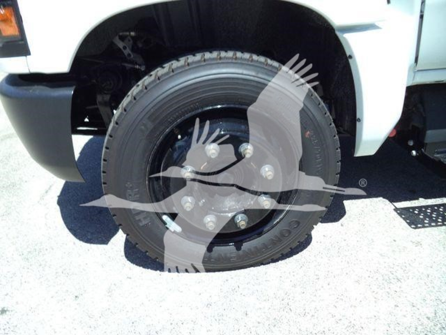 Truck wheel close-up on front left, 2023 Chevrolet Silverado 6500HD inroll-off configuration showing steel wheel with lug nuts and tire.