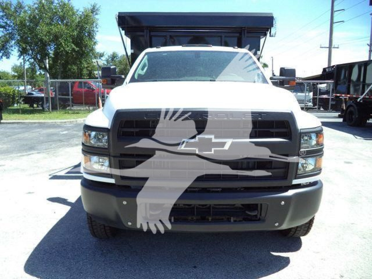 Front view of a white Chevrolet Silverado 6500HD roll-off truck, with black grille and bumper, large hood, and dump bed visible; Chevrolet bowtie logo on grille.