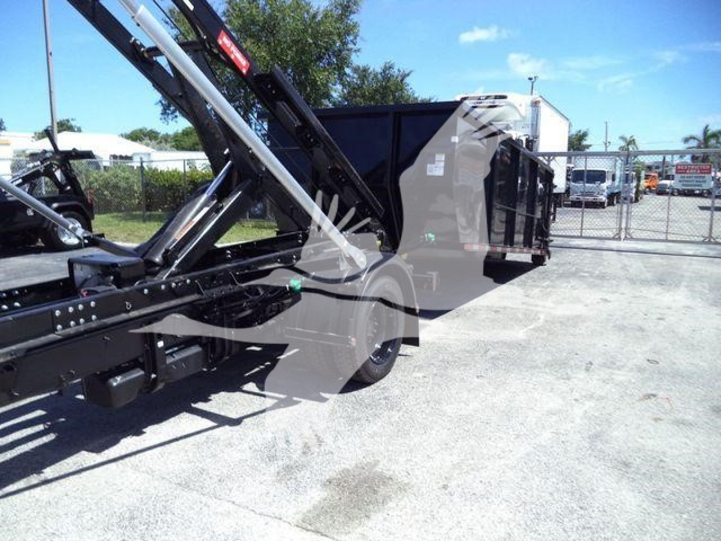 Chevrolet Silverado 6500HD roll-off truck with hydraulic arm and dump bed shown from side.