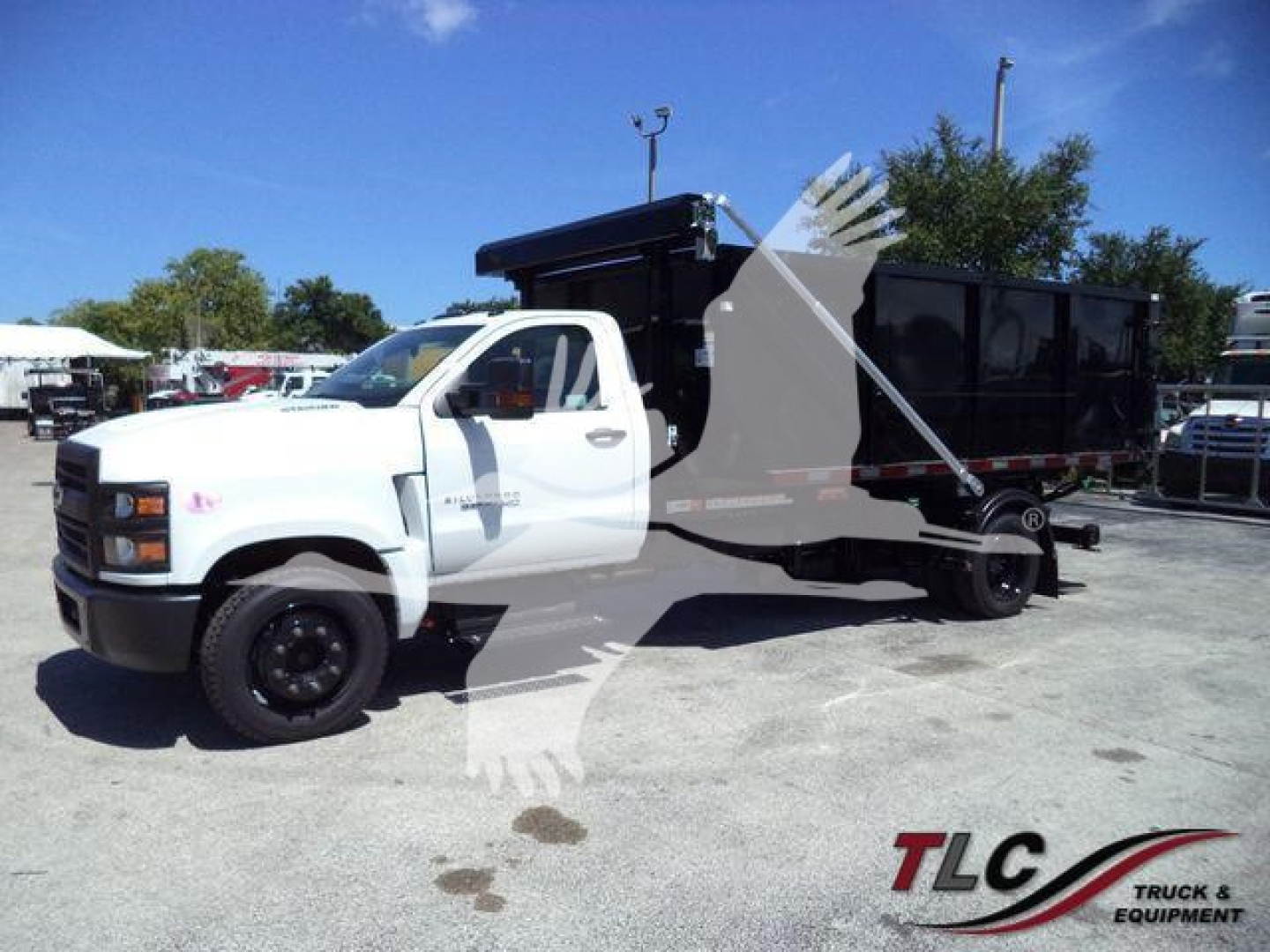 Chevrolet Silverado 6500HD rolloff truck in white, side view showing dump body and rear hopper, stock number J05526FM.