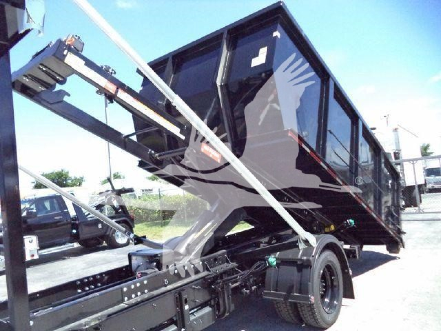 Truck bed view showing a Chevrolet Silverado 6500HD roll-off truck with hydraulic arms and black cab and dump bed