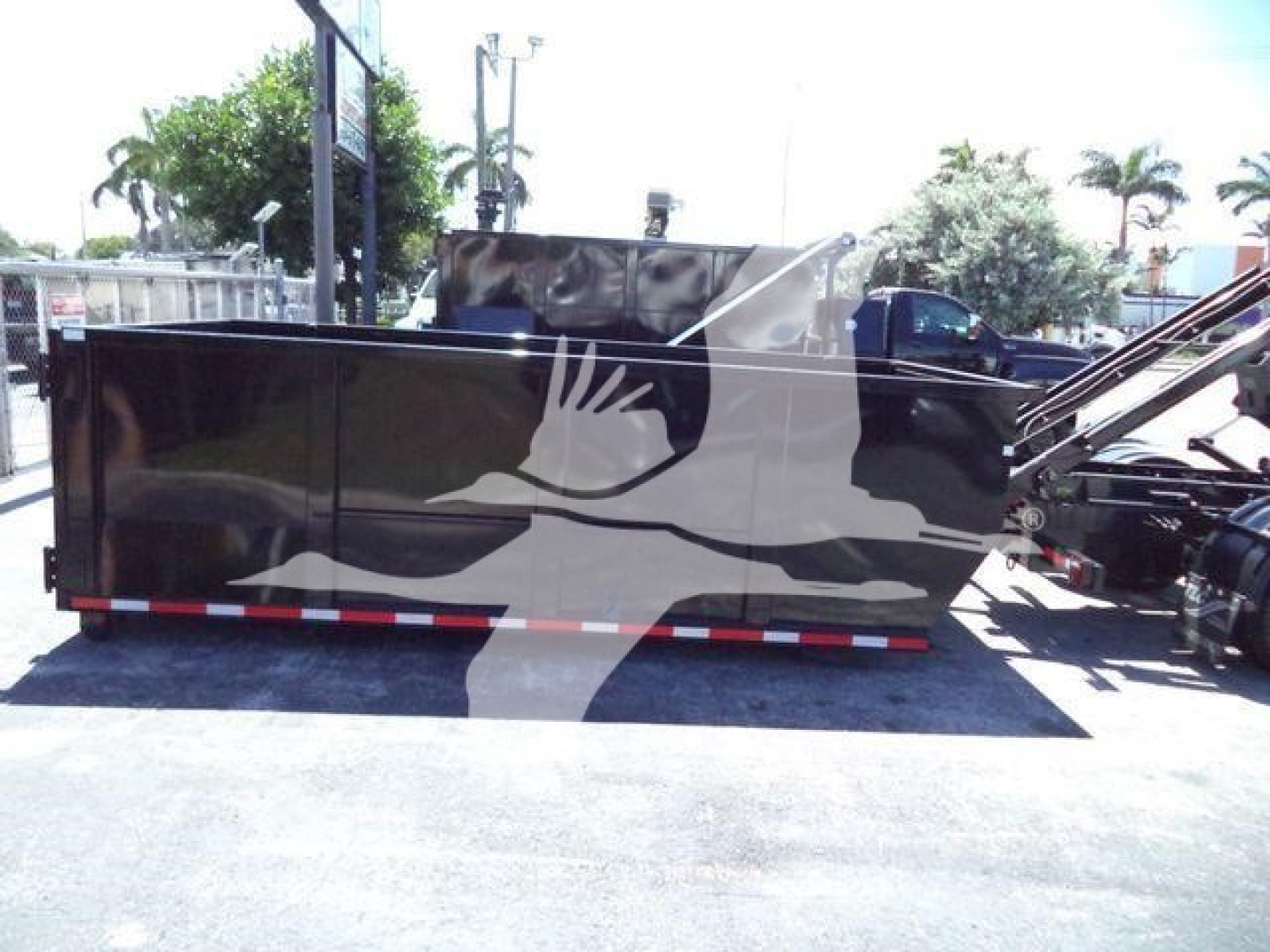 Roll-off truck body with black paint and a large white graphic on the side, showing a stylized hand and wave pattern, rear-view including reflective tape along bottom edge.