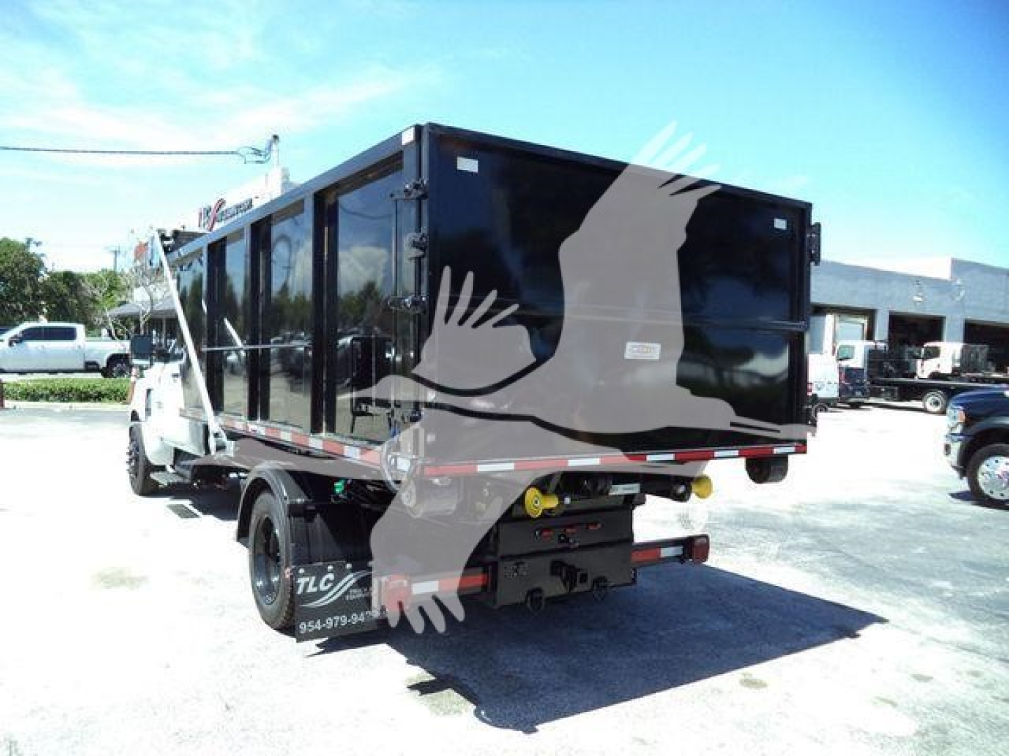 Truck bed showing cargo trailer with black exterior and rear hitch, viewed from rear-left angle.