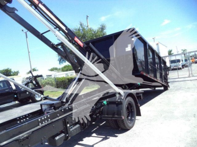 Truck bed area of a 2023 Chevrolet Silverado 6500HD roll-off with hydraulic arms and black dump body visible.