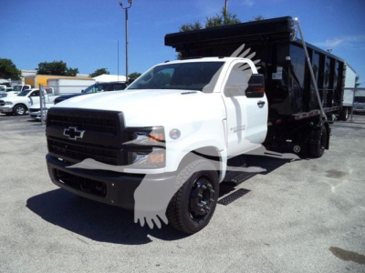 Chevrolet Silverado 6500HD dump truck side view showing white cab and black dump body with dual rear wheels.