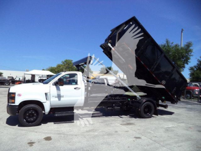 Truck with tilt-bed dump body in raised position, white Chevy Silverado 6500HD, roll-off style
 shows dumping bed and hydraulic components.