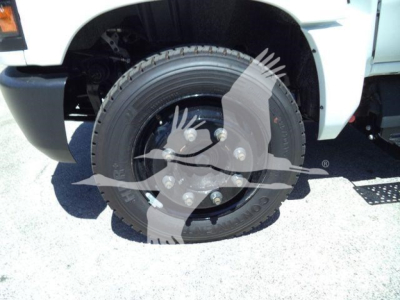 Truck wheel close-up on front left, 2023 Chevrolet Silverado 6500HD inroll-off configuration showing steel wheel with lug nuts and tire.