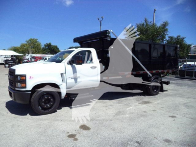 Truck in yard showing a white 2023 Chevrolet Silverado 6500HD roll-off body with black dump container. Vehicle side view labels visible.