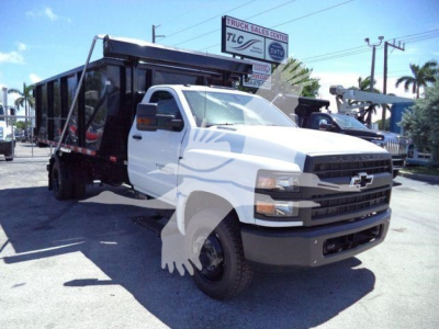 Truck with a white Chevrolet Silverado cab and a black dump bed, front view, in a dealership lot.