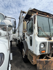 Truck wrecking body showing garbage truck with crane in side view, worn white cab and front bumper, rust accents, crane arm and hopper visible.