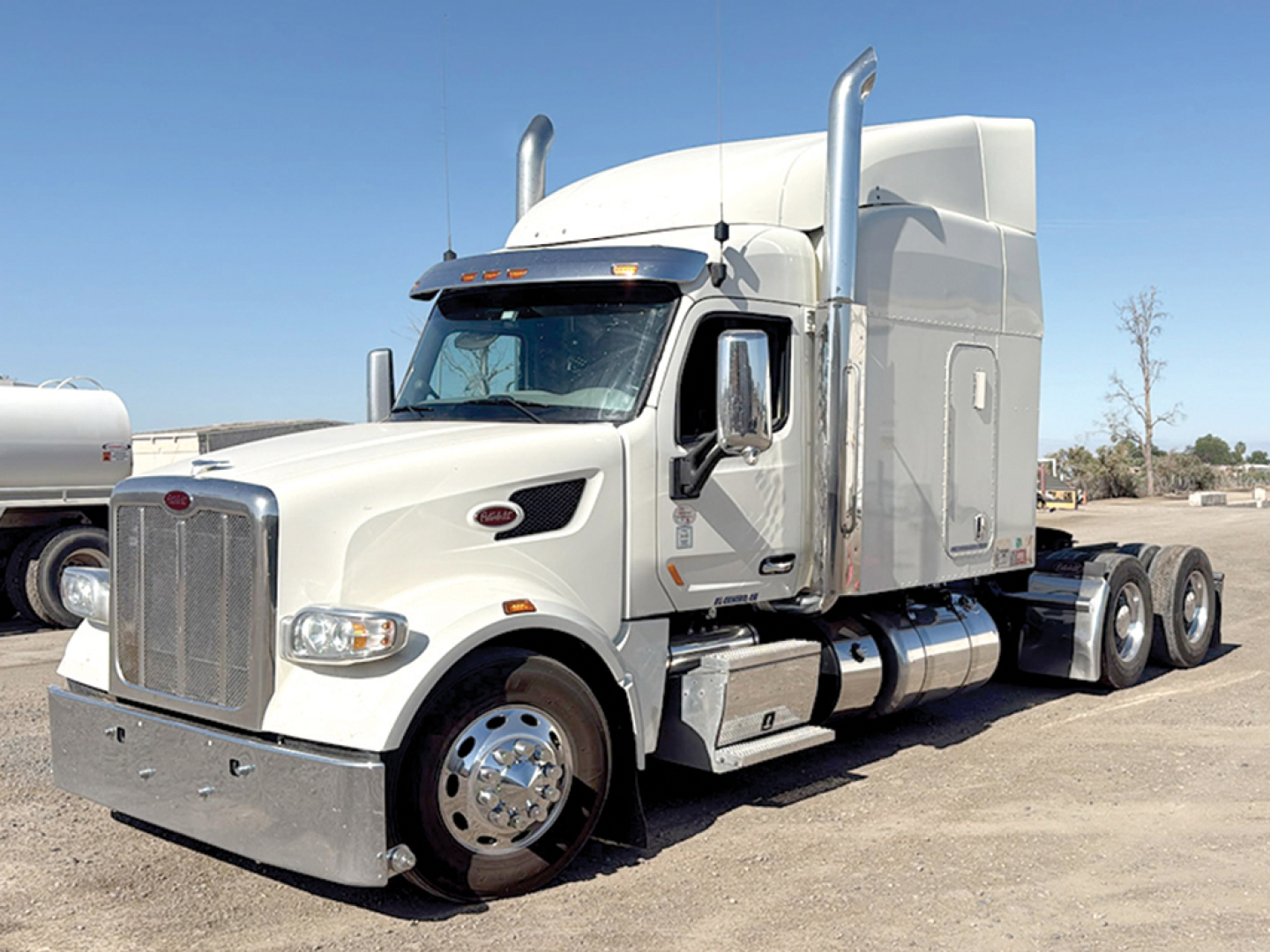 Peterbilt 567 UltraCab tractor in light gray, front grille, chrome bumper, dual exhaust stacks, large fuel tanks, 6x4 configuration, chrome wheels.