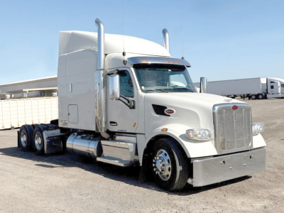 Peterbilt 567 UltraCab tractor truck in white, side view showing chrome grill, dual exhaust stacks, and sleeper cab.