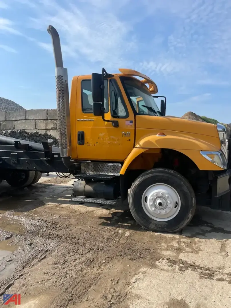 Dump truck side view showing tall exhaust, yellow cab with black steps, and chrome wheel hub; no body on dump bed.