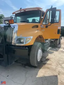 Front-left view of a yellow 2004 International 7400 dump truck with no body, showing the cab and front bumper and wheel.