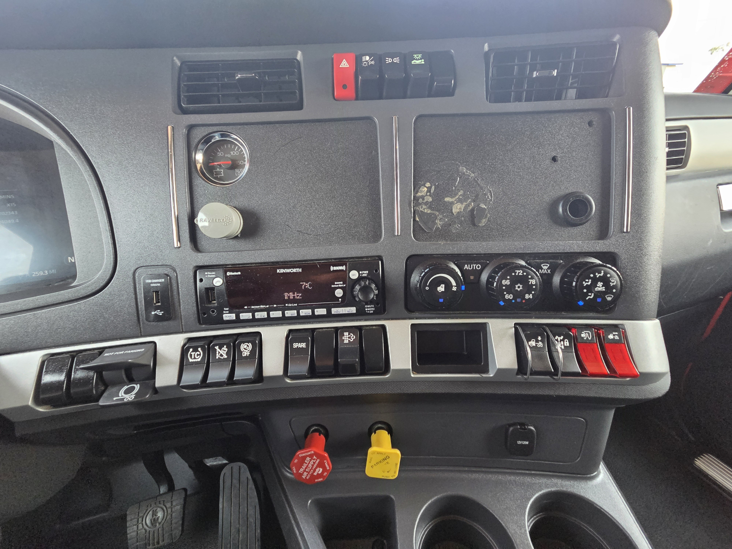 Kenworth truck cab dashboard and controls visible with gauges, vents, switches, and ignition area; dashboard shows various knobs and a faded panel.
