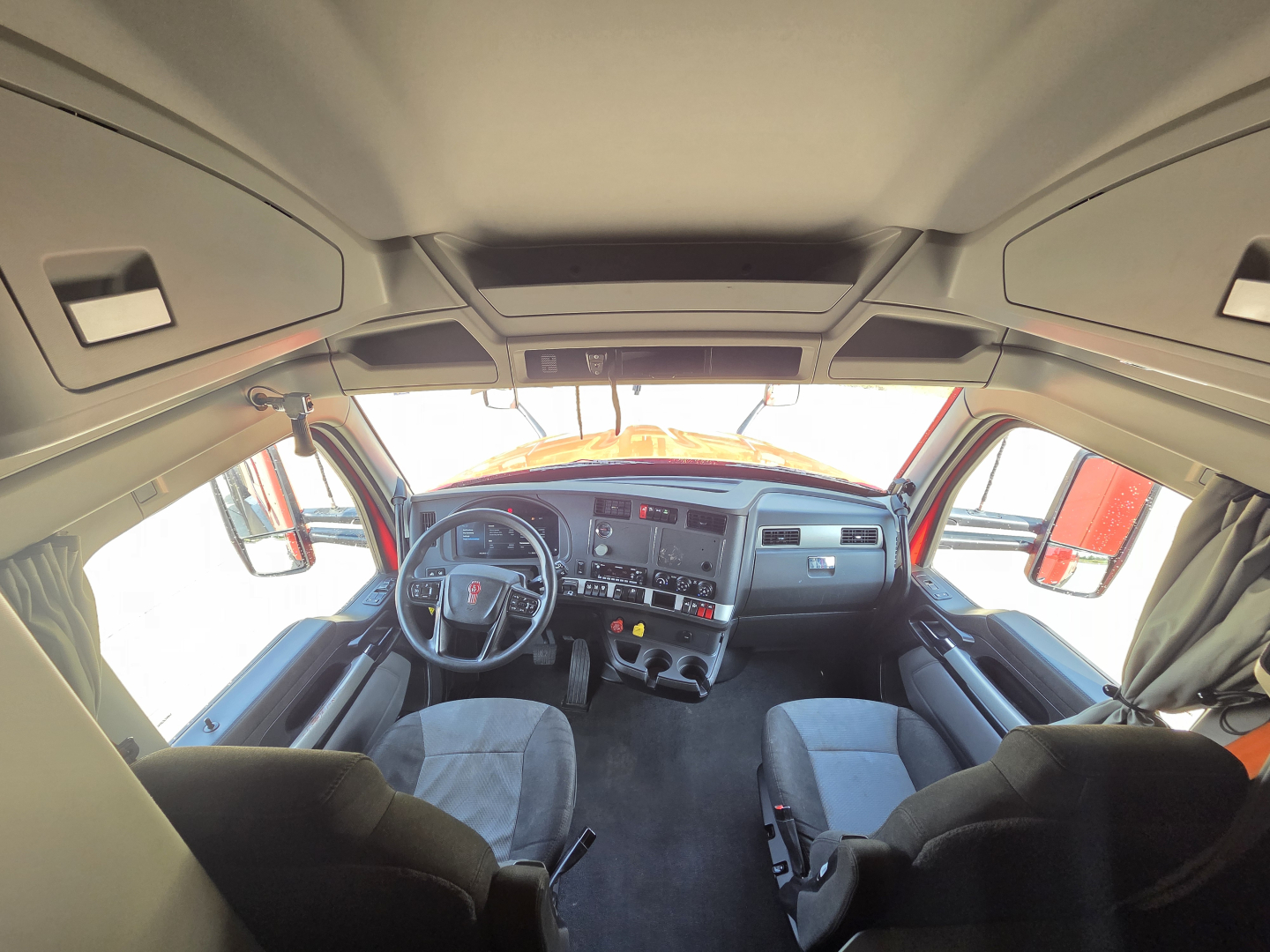 Kenworth T680 truck cab interior view showing steering wheel, dashboard, and driver seats.
