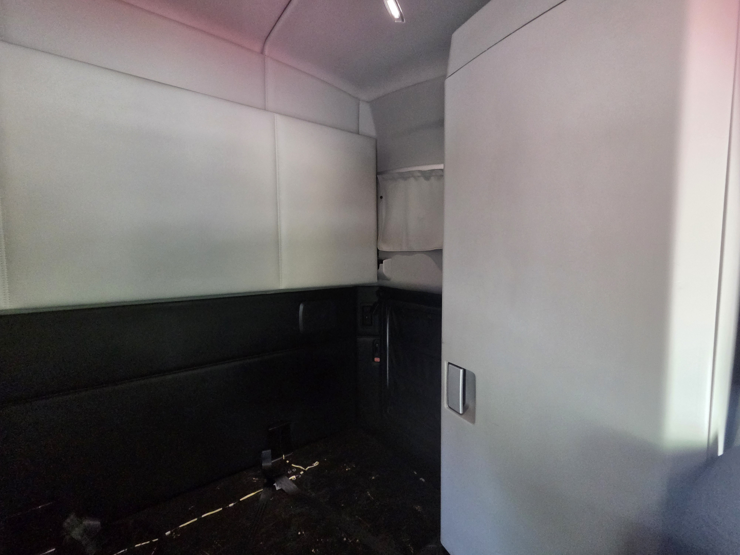 Kenworth T680 cab interior rear sleeper area with windowless side panels and storage cabinet