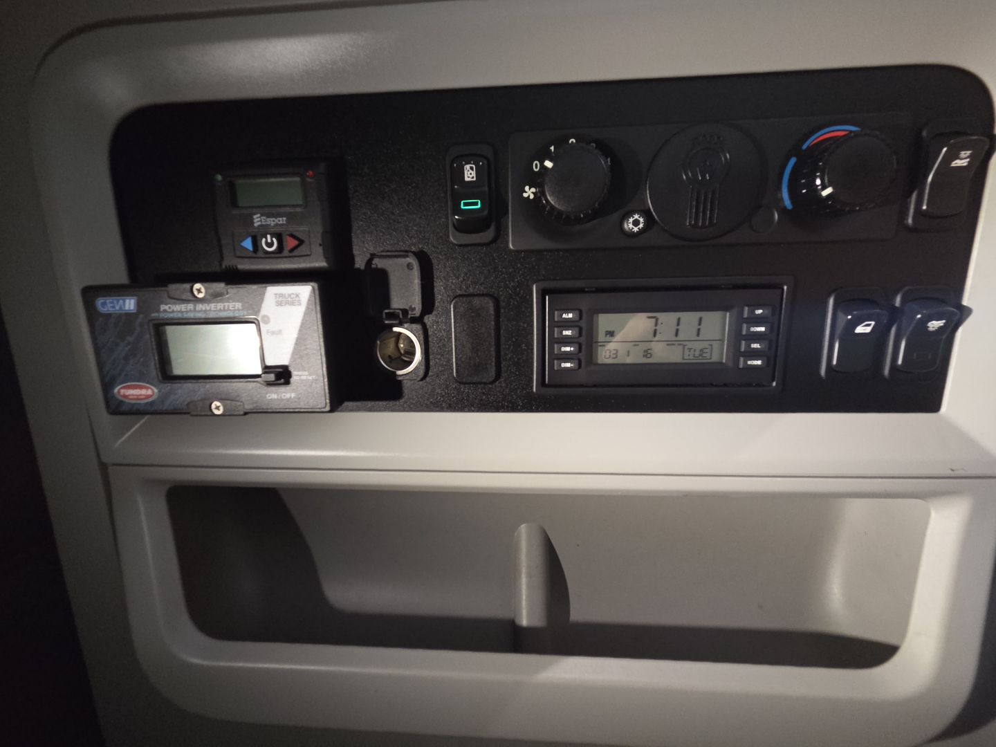Kenworth T680 dash area showing control panel with gauges, vents, and a digital display panel. Visible text includes ‘KENWORTH’ badge, and various control labels around a climate control knob and stereo.