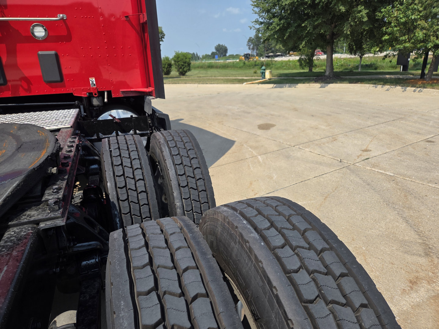 Rear wheels and chassis of a red Kenworth truck showing dual rear axles and tire treads.