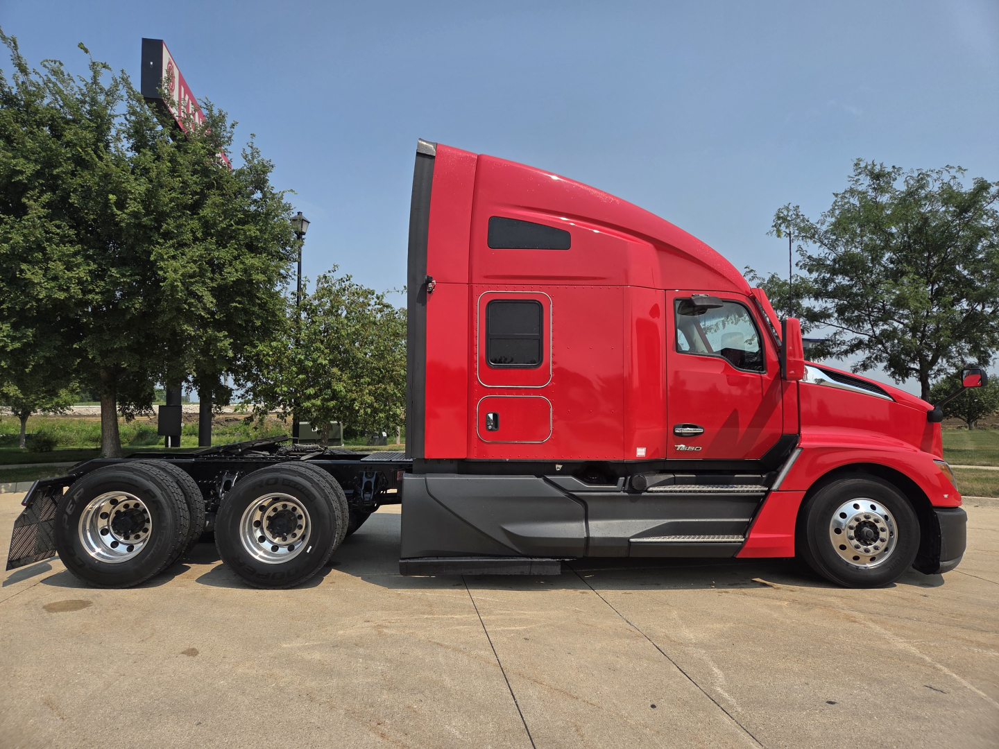 Kenworth T680 conventional sleeper truck side view showing red cab with aerodynamic lines and dual rear axles.