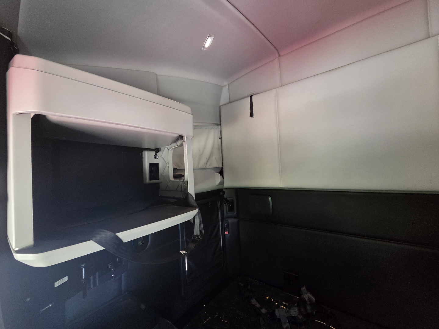 Kenworth T680 sleeper cab interior showing overhead bunk area and storage with hydraulic shelving and control panels.