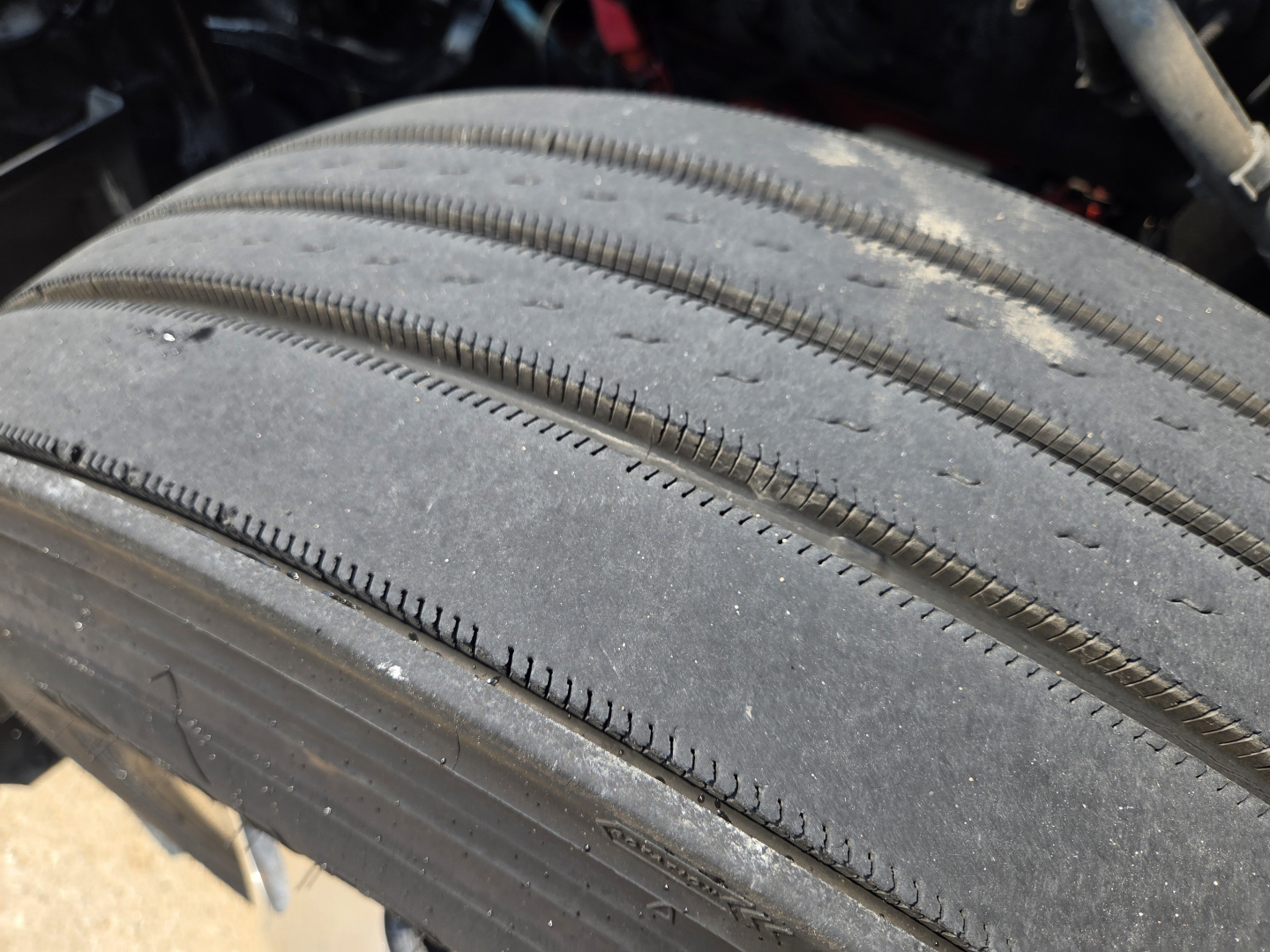 Tread view of a truck tire shown from side, with visible rib patterns and wear along the tread.