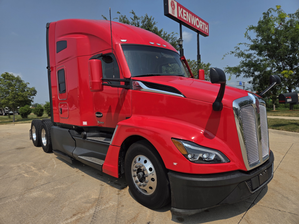 Kenworth T680 front-left view showing red sleeper cab and chrome grille, side mirror, and wheel wells.