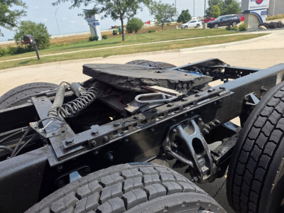 Kenworth truck chassis and suspension components with dual rear wheels and damaged hood area.