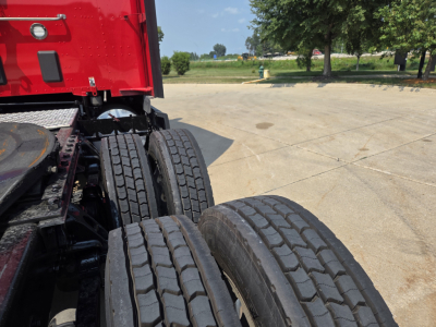 Rear wheels and chassis of a red Kenworth truck showing dual rear axles and tire treads.