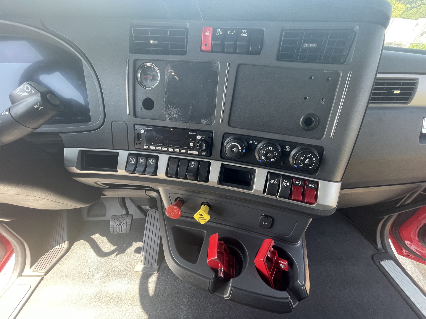 Kenworth T680 dashboard and center console showing various switches, gauges, and pedals in the cab.