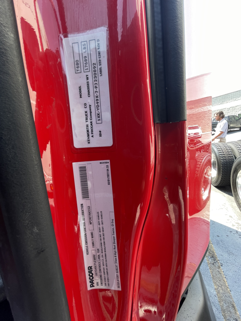 Vehicle VIN/stock labels on the door jamb of a red Kenworth T680: barcodes and text blocks with serial numbers and stock info. Visible text includes VIN 1XKYD49X0NJ488502 and stock number 0628305.