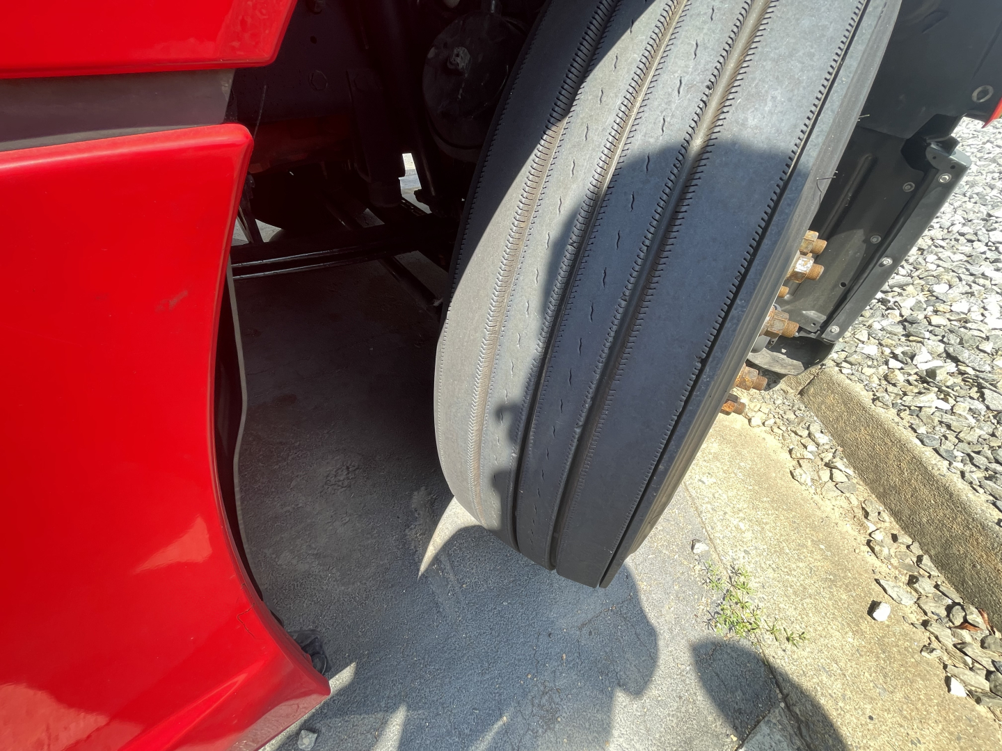 Kenworth T680 front wheel and red fender with tire in wheel well, part of a sleeper cab truck.