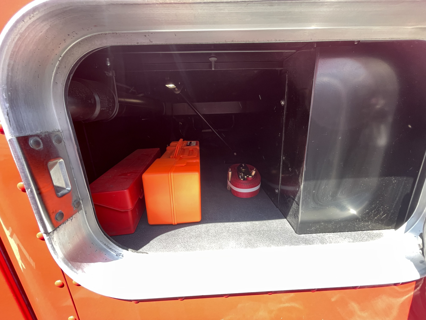Trunk/storage area of a 2022 Kenworth T680 with two battery boxes and a red circular device visible.