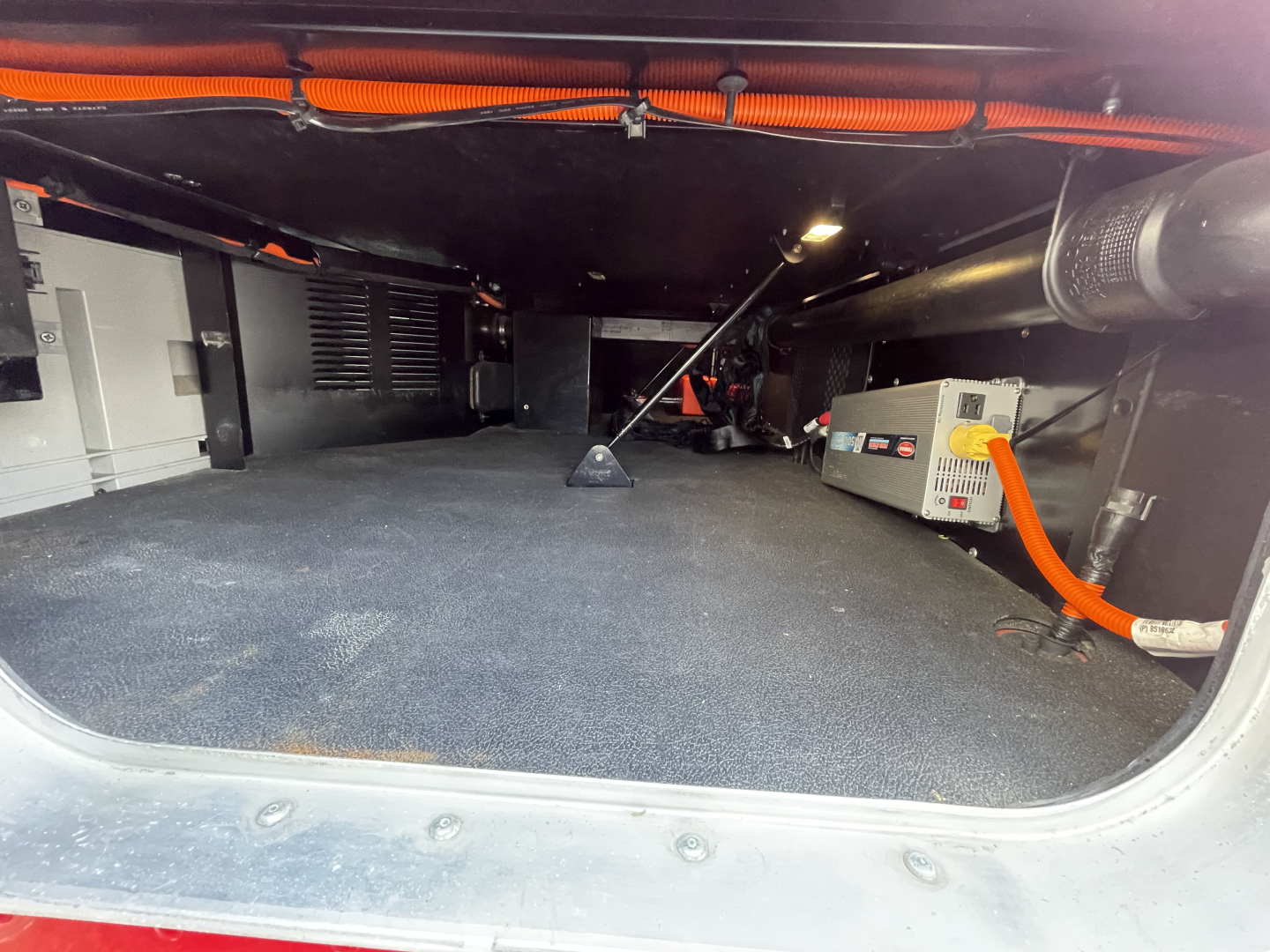 Kenworth T680 undercarriage inside cargo area showing engine bay equipment and cables