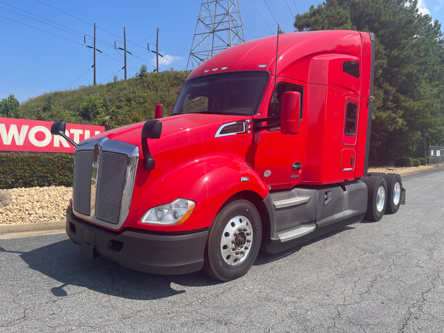 Kenworth T680 truck in red cab, side view showing cab doors and front grille.