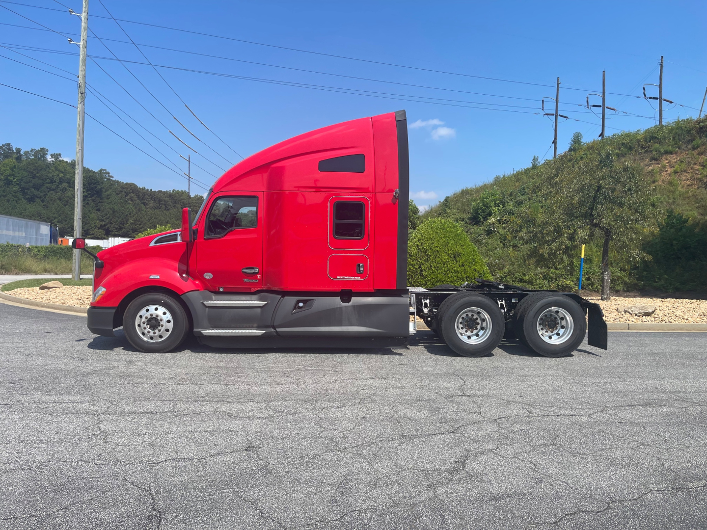 Kenworth T680 semi truck in red, side view with sleeper cab and dual rear axles, no visible text on the vehicle.