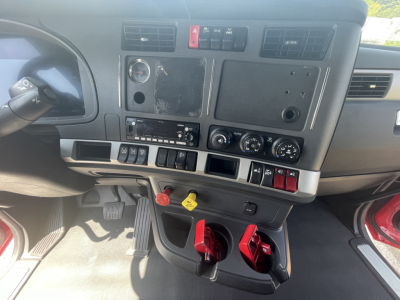 Kenworth T680 dashboard and center console showing various switches, gauges, and pedals in the cab.