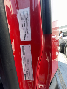 Vehicle VIN/stock labels on the door jamb of a red Kenworth T680: barcodes and text blocks with serial numbers and stock info. Visible text includes VIN 1XKYD49X0NJ488502 and stock number 0628305.