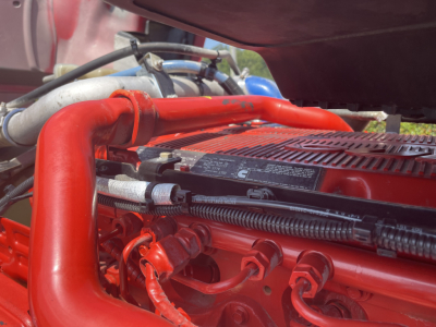 Kenworth T680 engine bay showing red intake manifold and hoses.