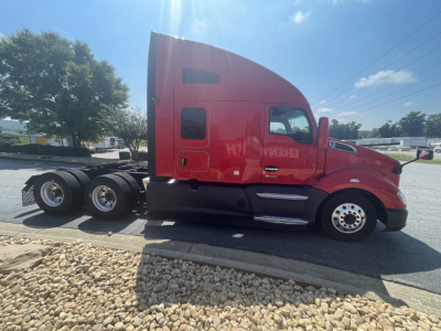 Kenworth T680 truck side view showing red sleeper cab and triple rear axles with chrome steps and wheels.