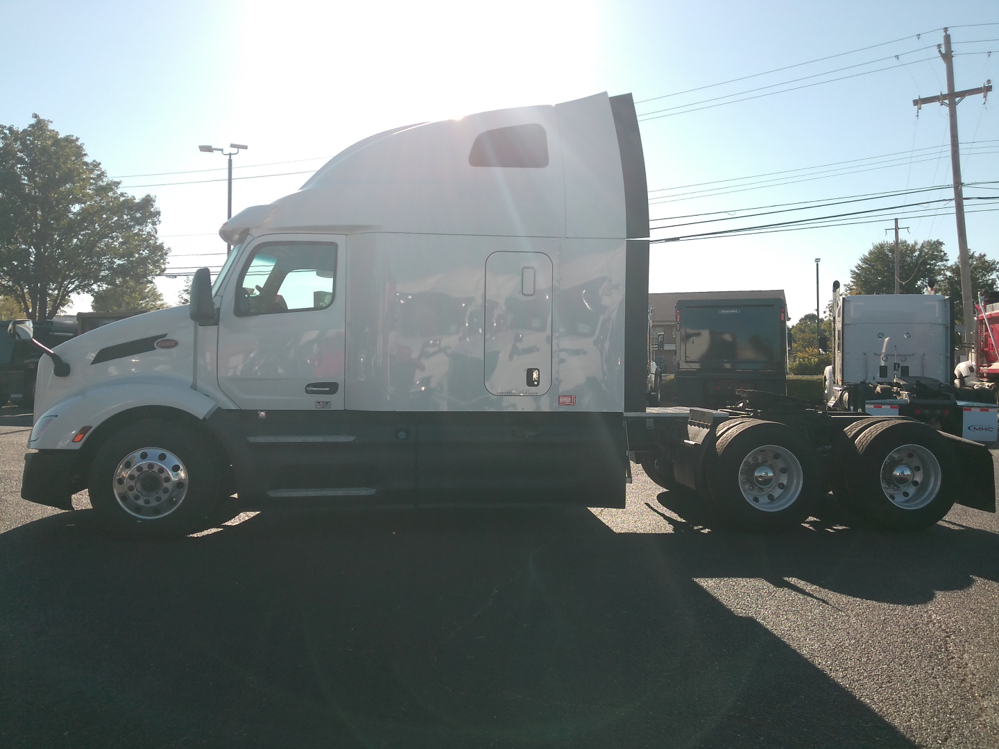 Peterbilt 579 conventional sleeper truck side view showing cab and chassis with sleeper cab, white color, wheel treads, and triaxle rear configuration.