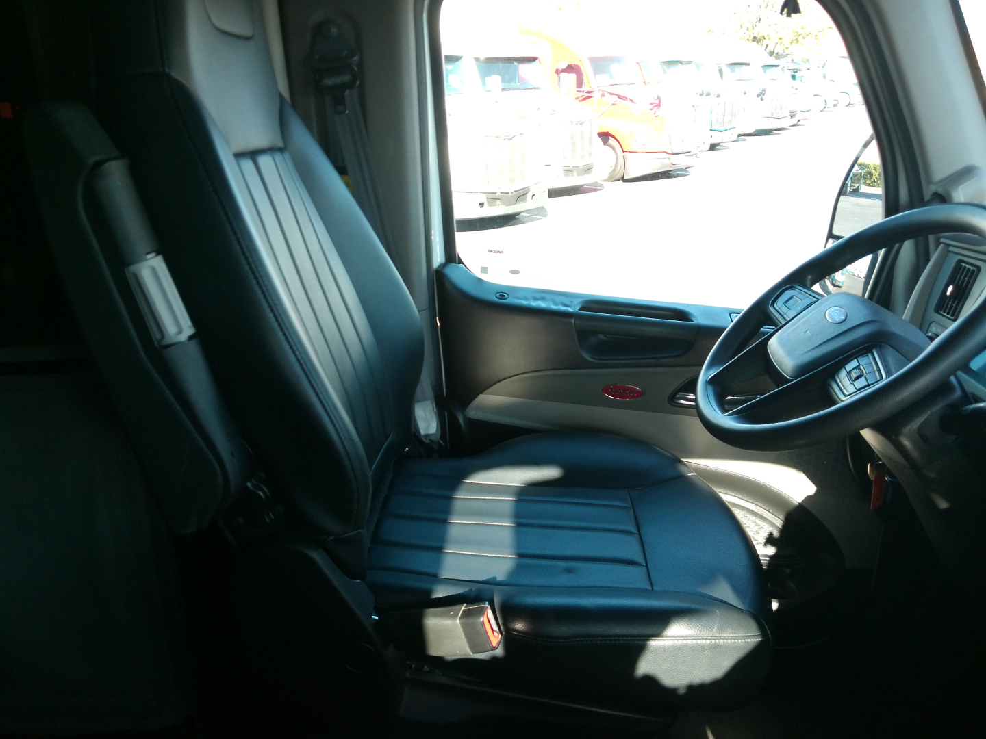 Peterbilt 579 truck interior driver seat and steering wheel, with view of the dashboard and side window.