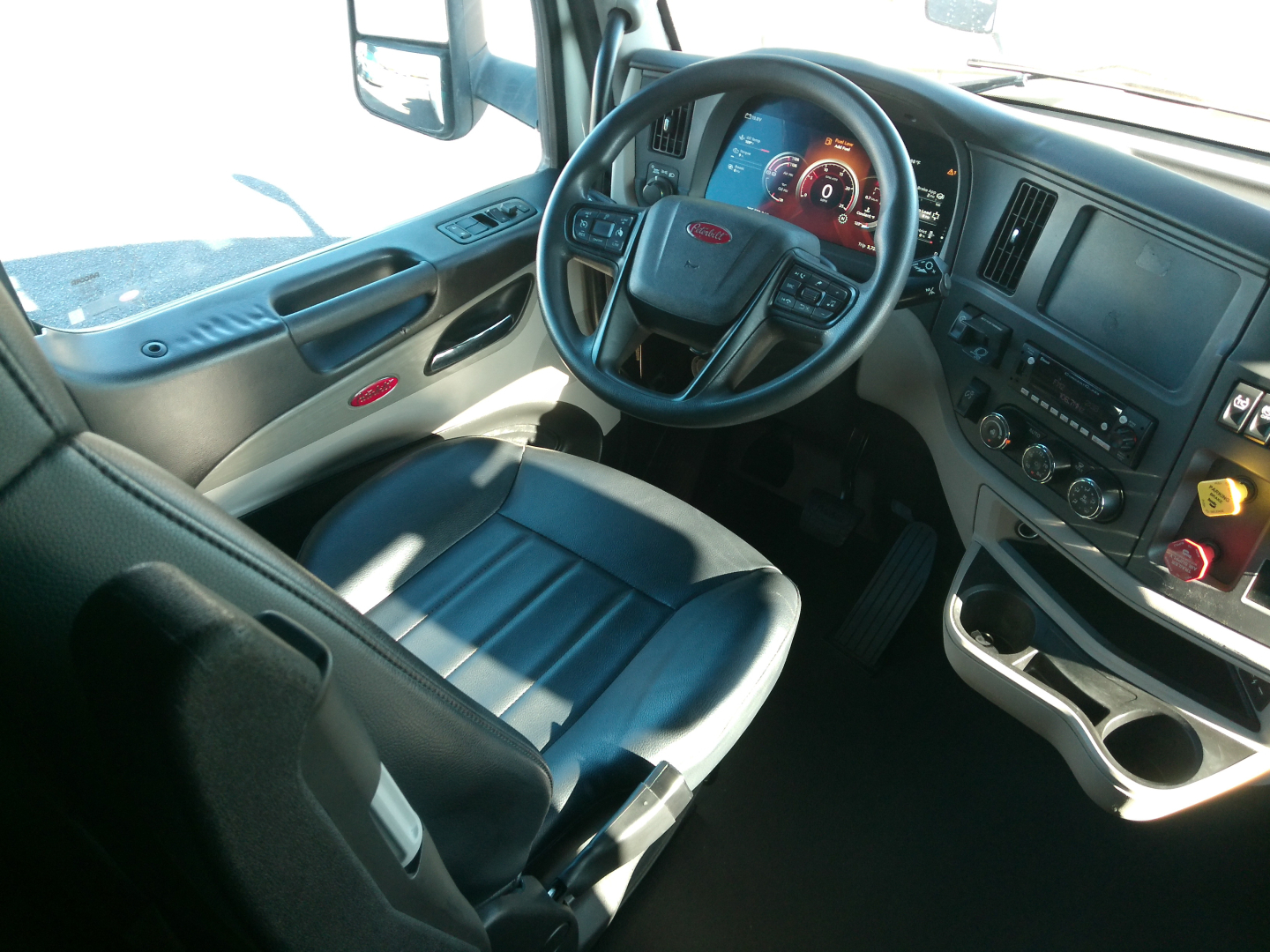 Peterbilt 579 truck interior showing steering wheel, dashboard with gauges, center console, and driver's seat.