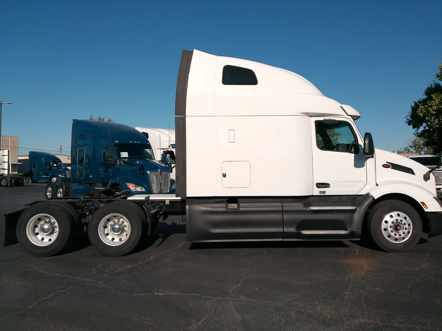 Peterbilt 579 tractor unit side view showing sleeper cab, white exterior, black lower panels, and chrome wheels.
