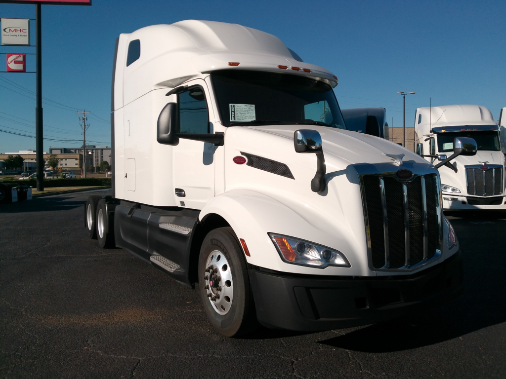 Peterbilt 579 conventional sleeper truck in white parked at a dealership, front three-quarter view showing cab and grille, with stock number 0631721 visible.