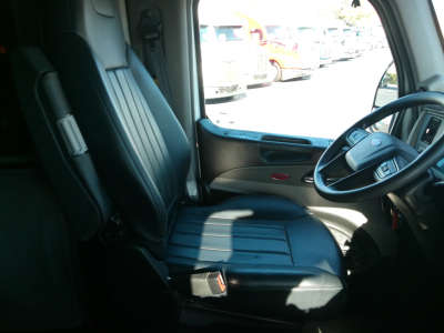 Peterbilt 579 truck interior driver seat and steering wheel, with view of the dashboard and side window.
