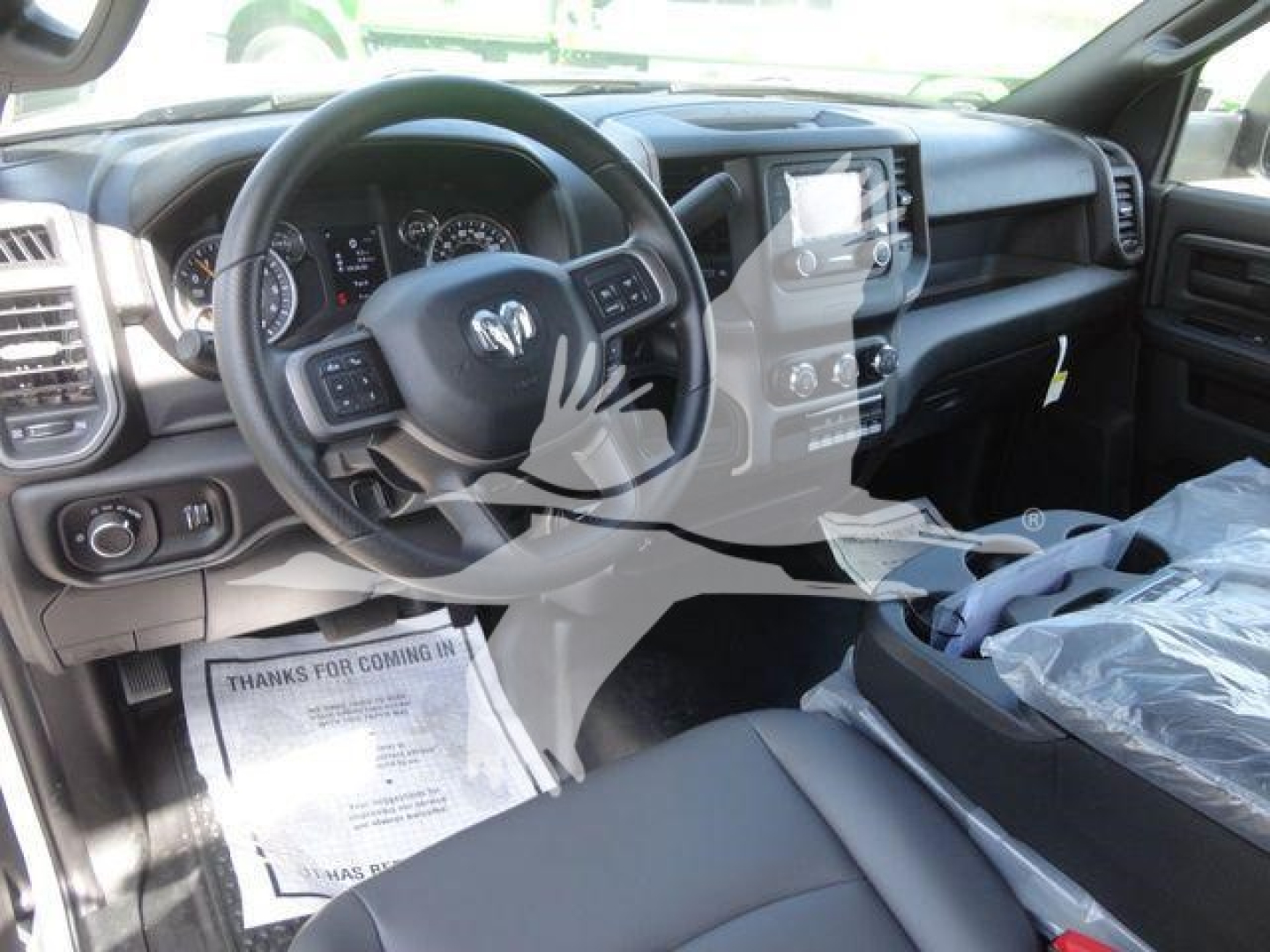 Ram steering wheel with dashboard and center console of a new 2024 Ram 5500 HD truck interior. Visible text includes a floor mat with 'THANKS FOR COMING IN' and the infotainment screen area.