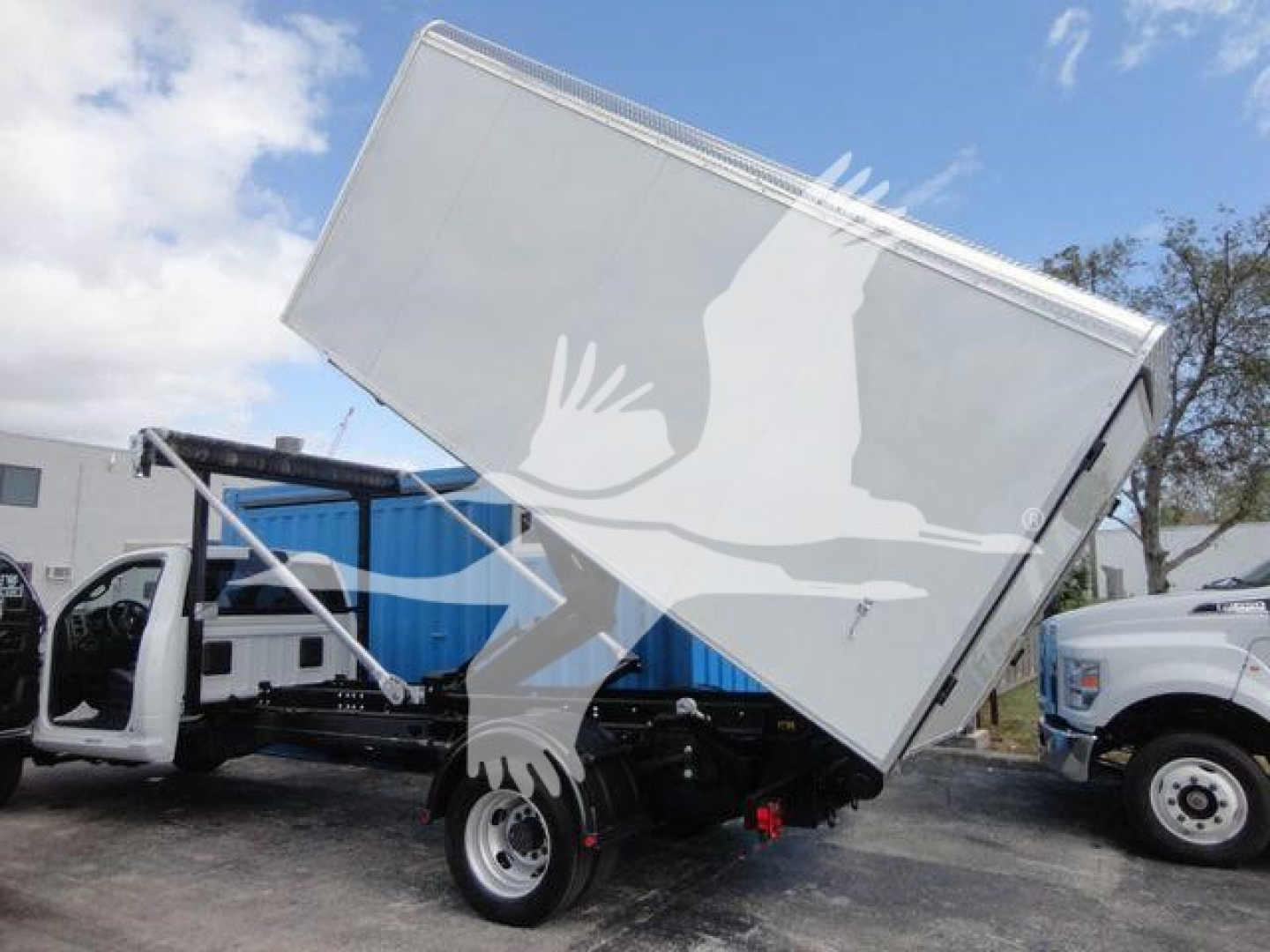 Truck cab with a raised dump bed on a RAM 5500 HD roll-off, side view showing the front wheel and yellow and black chassis tag.