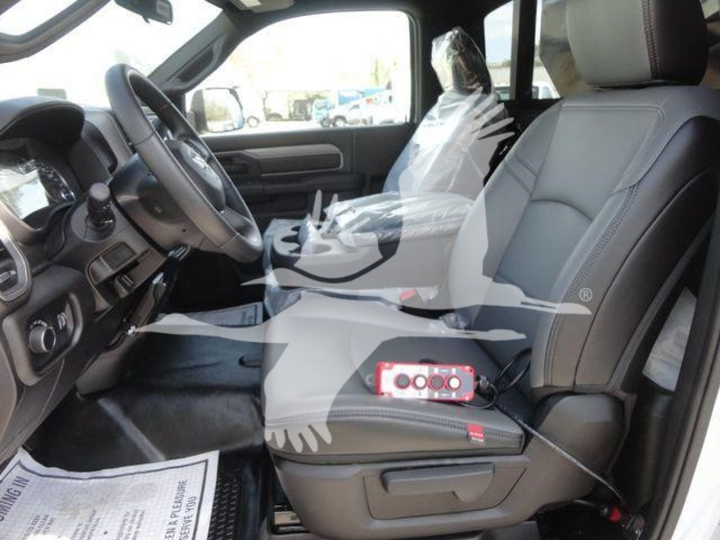 Ram 5500 HD interior view showing driver seat and front passenger seat with steering wheel, center console, plastic-wrapped seat, and dashboard details.