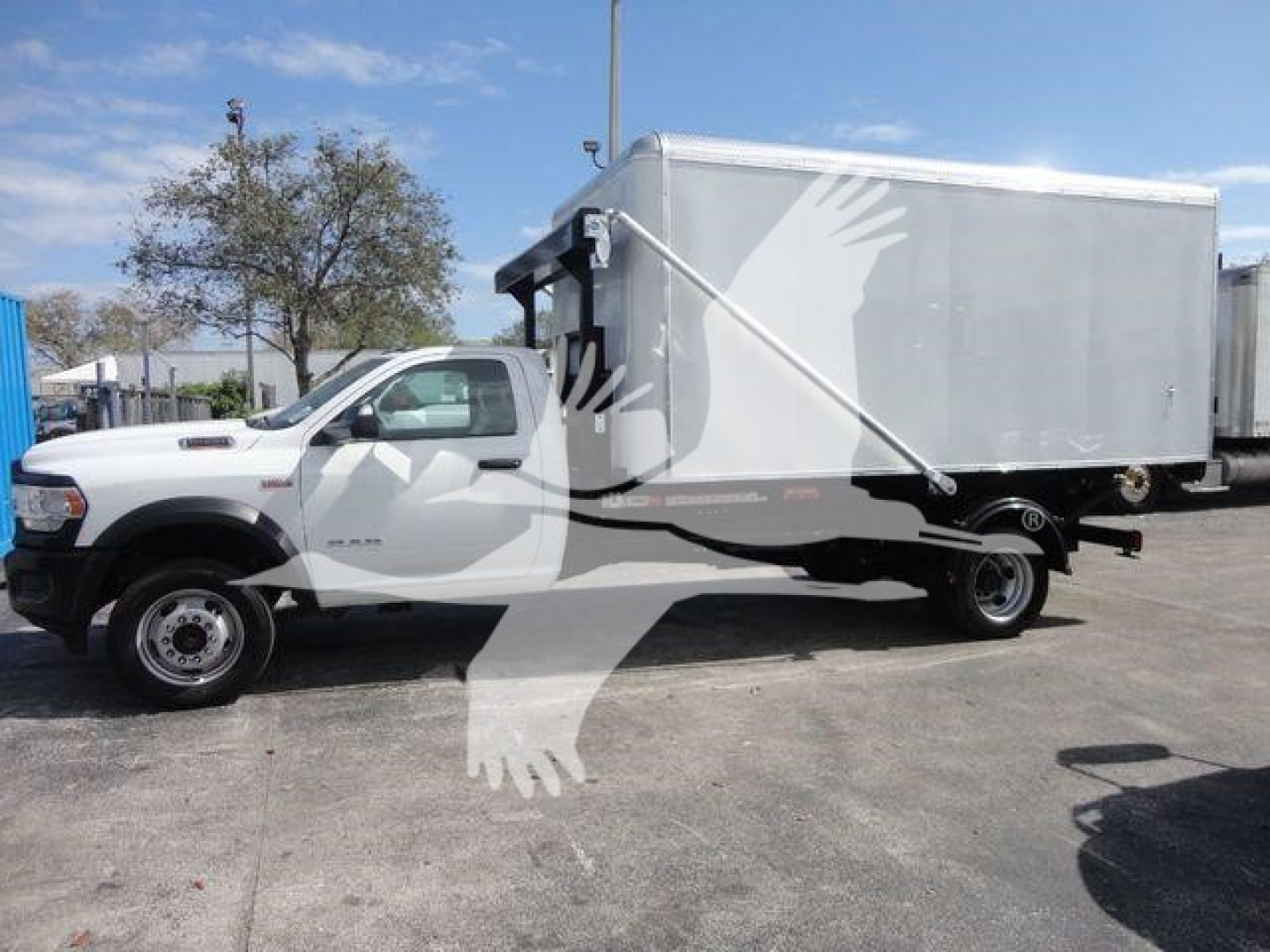 Ram 5500 HD roll-off truck with a large gray box, side view showing cab and box, no discernible labels visible on the truck body.